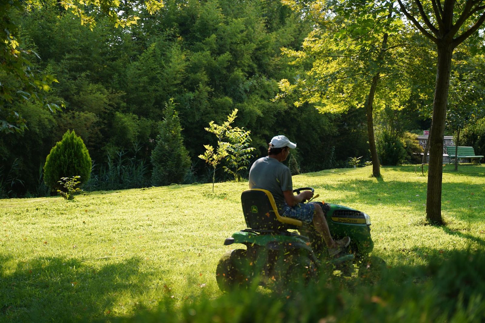 Mann mäht an einem sonnigen Tag den Rasen im Garten